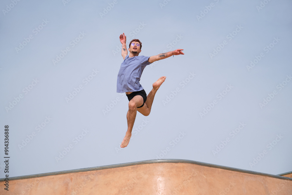Obraz premium Young man performing choreography jumping in the air in a skate park