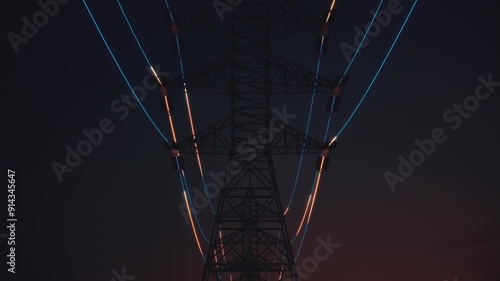 Power Transmission lines at night with Digital Electricity flow. Forward-moving  loopable camera highlights towering pylons against a starry sky.  Ultra HD 4K 3D animation