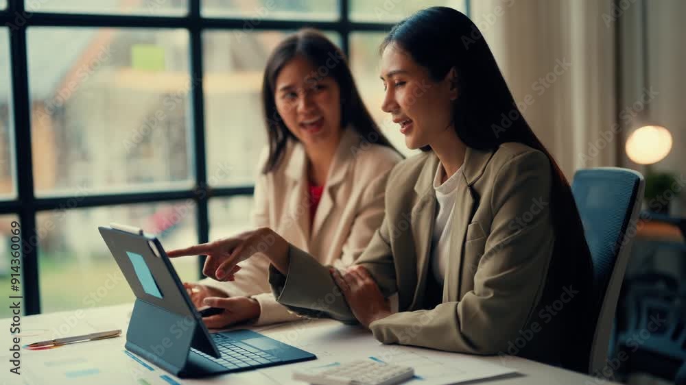 Two businesswomen collaborating on a laptop in a modern office. Engaged in teamwork and brainstorming with a bright and professional setting Two businesswomen collaborating on a laptop in a modern office. Engaged in teamwork and brainstorming with a bright and professional setting