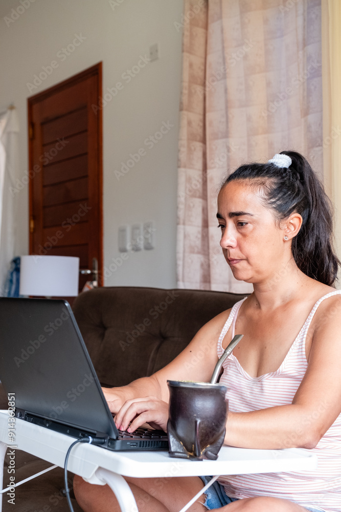 A woman is sitting at a table with a laptop and a cup of coffee A woman is sitting at a table with a laptop and a cup of coffee