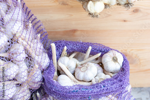 Garlic in a bag against the background of a wooden wall, harvest, preparations for the winter. High quality photo