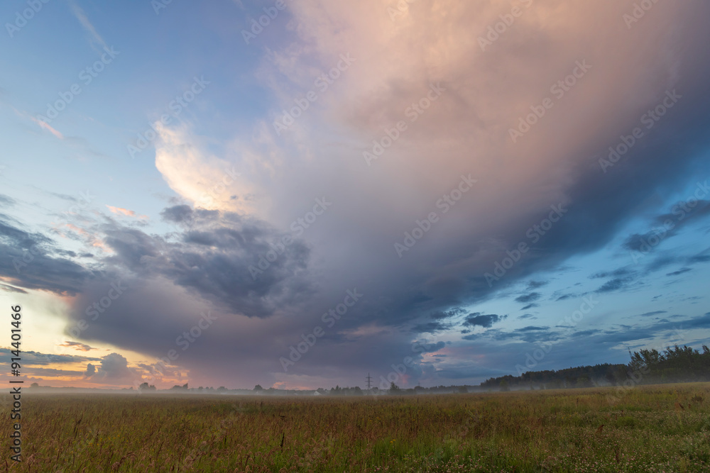 Fototapeta premium A large cloud is in the sky, and the sun is setting