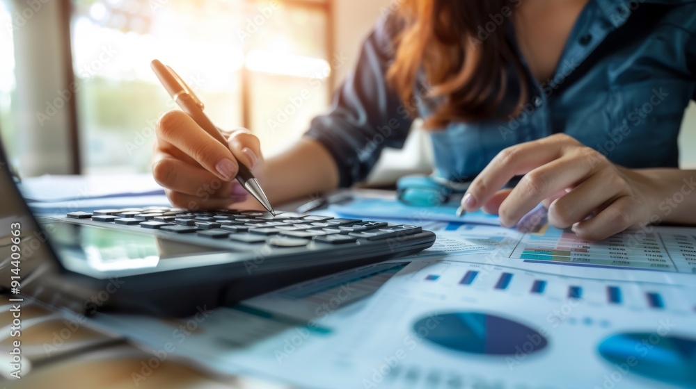 Woman accountant use calculator and computer with holding pen on Woman accountant use calculator and computer with holding pen on
