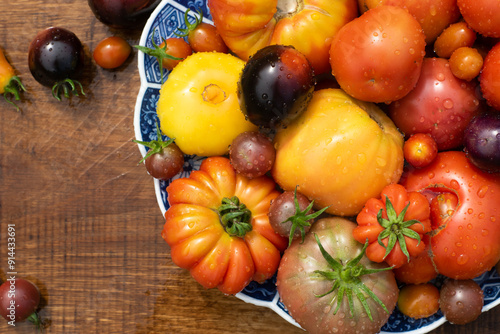 Obraz na płótnie Many garden tomatoes in different colors, shapes and varieties on a blue rustic plate on a wooden table. Tomatoe composition with space for text. w salonie