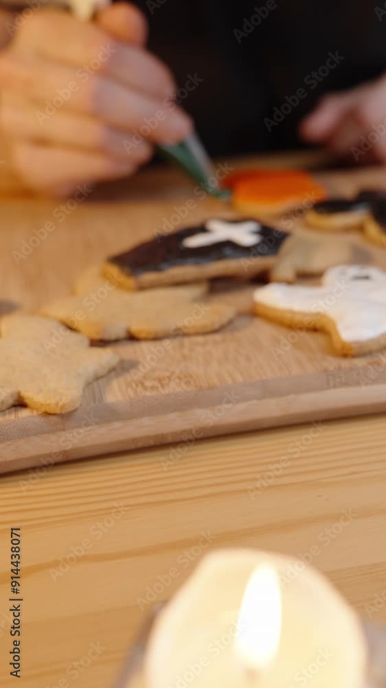 Vertical video. Preparing for Halloween, Mini Pumpkins on the Table Being Moved Aside While a Woman Paints Gingerbread Cookies in the Shape of Holiday Symbols with Sugar Icing. Vertical video. Preparing for Halloween, Mini Pumpkins on the Table Being Moved Aside While a Woman Paints Gingerbread Cookies in the Shape of Holiday Symbols with Sugar Icing.