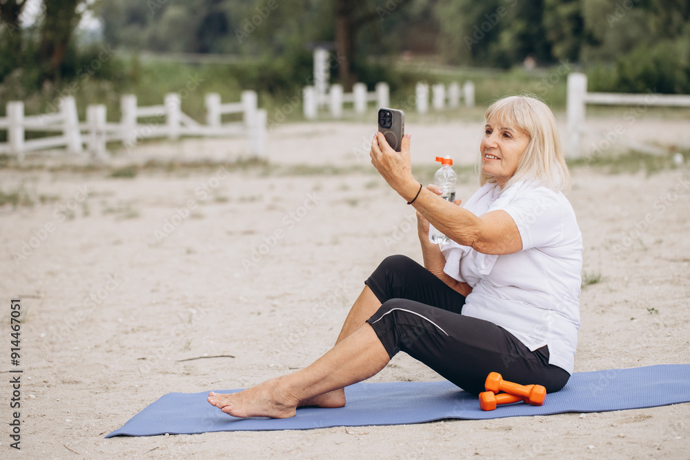 Senior Woman Exercising Outdoors, Taking a Selfie on a Beach Mat Senior Woman Exercising Outdoors, Taking a Selfie on a Beach Mat