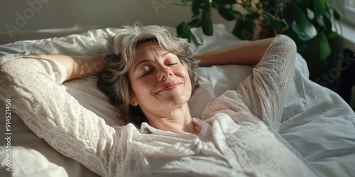 A woman lies in bed with her eyes closed, conveying a sense of relaxation and restfulness photo