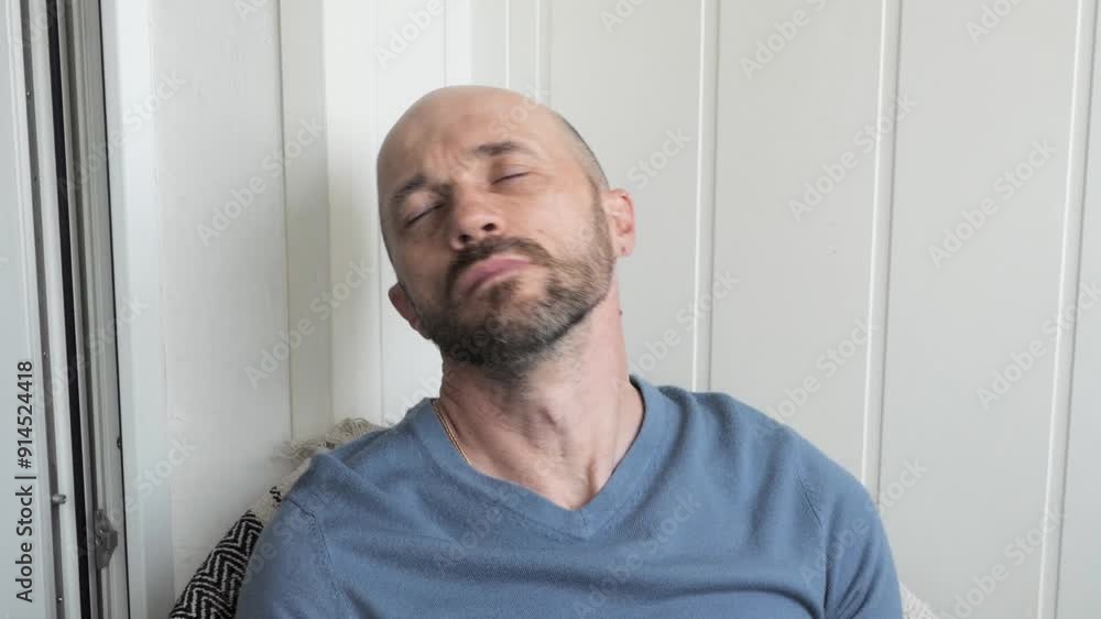 A man sitting in a chair is stretching his stiff neck A man sitting in a chair is stretching his stiff neck