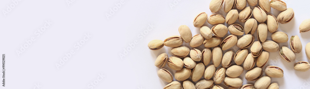 Pistachios on a white background. A handful of dry salted pistachios on a light background, selective focus. Pistachio with shell. Close-up Pistachios on a white background. A handful of dry salted pistachios on a light background, selective focus. Pistachio with shell. Close-up