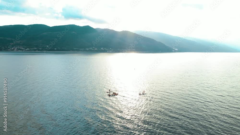 group swim of SUP surfers on boards with a paddle on the beautiful sea at dawn, aerial photography from a dron group swim of SUP surfers on boards with a paddle on the beautiful sea at dawn, aerial photography from a dron