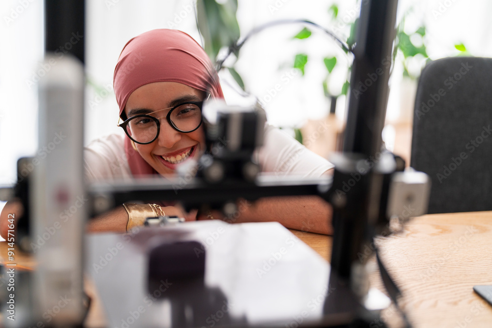 © Studio Marmellata - A woman in a dark red hijab smiles as she looks at the outcome of a 3D printing project. Her expression shows satisfaction and joy in the successful completion of the task. © Studio Marmellata - A woman in a dark red hijab smiles as she looks at the outcome of a 3D printing project. Her expression shows satisfaction and joy in the successful completion of the task.