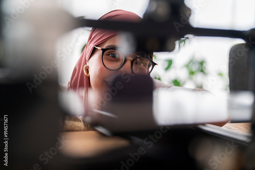 A woman in a dark red hijab examines the results of a 3D printing project, showcasing her attention to detail and the precision required in handling advanced technology. photo