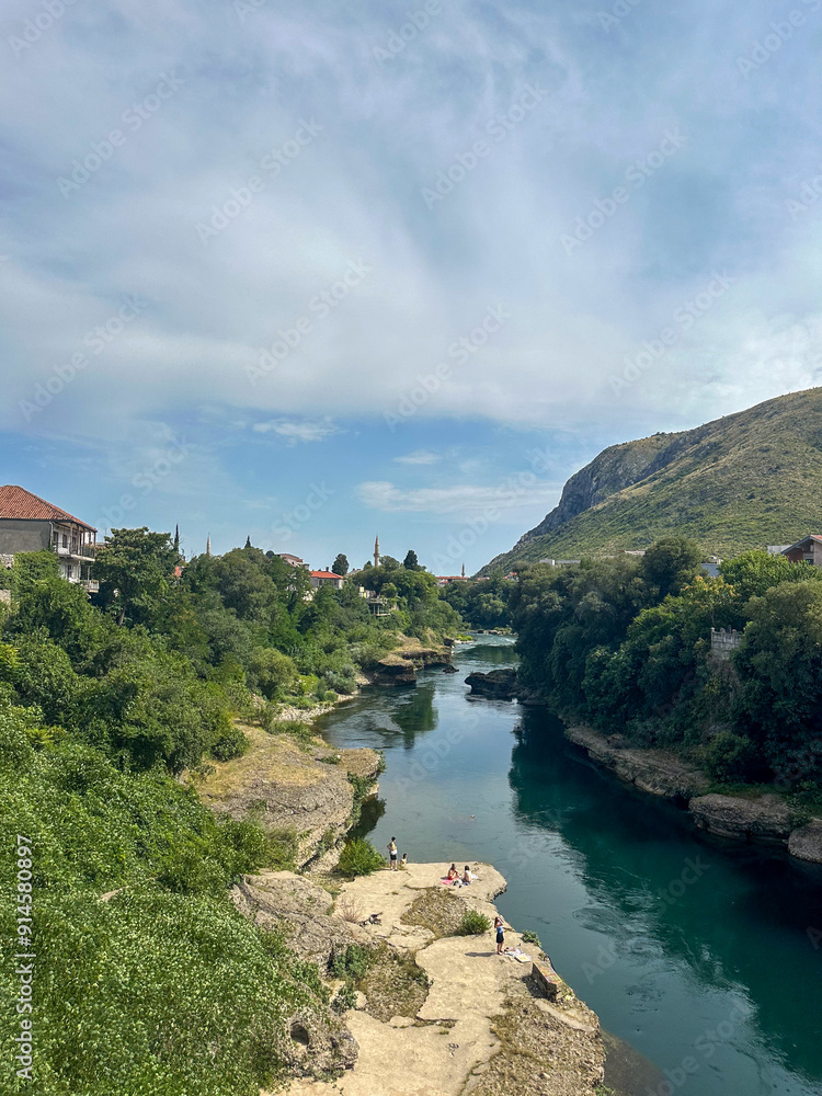 Naklejka premium Neretva River in Mostar with Trees and Rooftops in Background