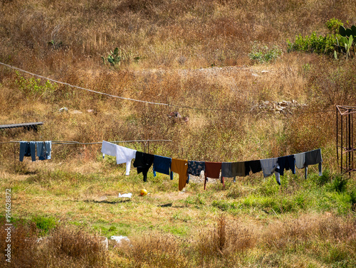Obraz na płótnie Clothes Hanging on a Rope in the Middle of a Vacant lot Filled with Long Yellow Grass w salonie
