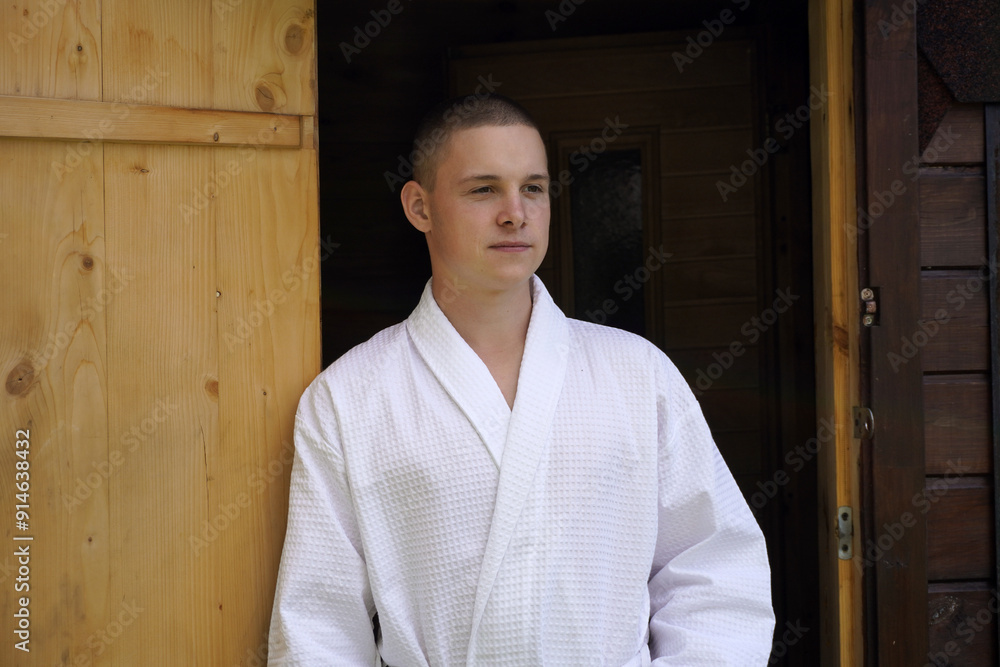 portrait is a close-up, the guy is standing near the bathhouse and preparing a broom of their fresh birch branches for bath procedures. portrait is a close-up, the guy is standing near the bathhouse and preparing a broom of their fresh birch branches for bath procedures.
