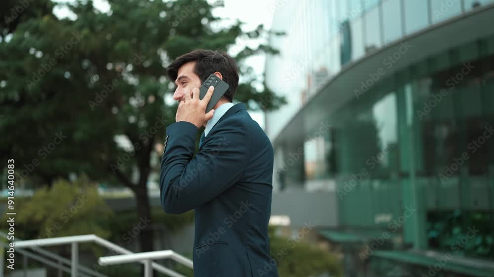 Skilled caucasian project manager calling phone while walking at city with blurred background. Skilled businessman using smart phone talking to project manager with blurred background. Exultant. Skilled caucasian project manager calling phone while walking at city with blurred background. Skilled businessman using smart phone talking to project manager with blurred background. Exultant.