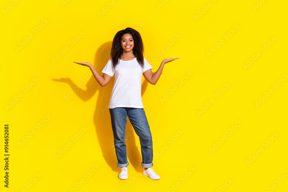 Full size photo of pretty young woman hold empty space scales wear t-shirt isolated on yellow color background Full size photo of pretty young woman hold empty space scales wear t-shirt isolated on yellow color background