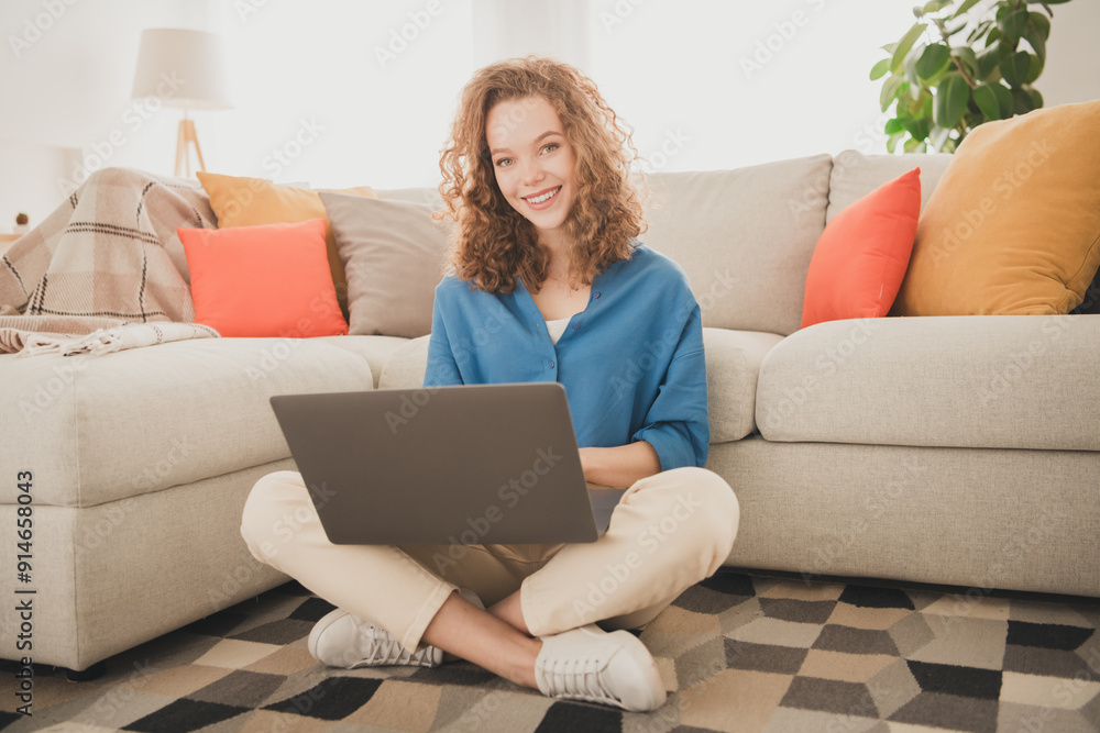 Full length photo of attractive trendy young woman sit floor netbook blue shirt move new apartment home interior indoors Full length photo of attractive trendy young woman sit floor netbook blue shirt move new apartment home interior indoors