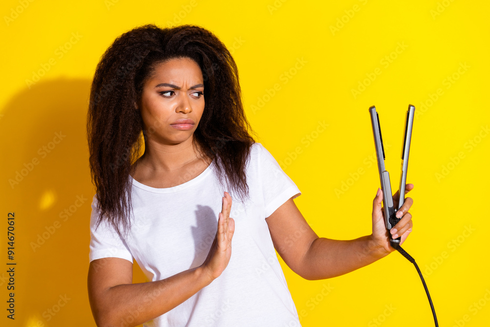 Photo of pretty young woman arm deny hair straightener wear t-shirt isolated on yellow color background Photo of pretty young woman arm deny hair straightener wear t-shirt isolated on yellow color background