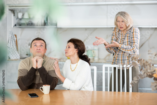 Canvas Print Kind woman asking livid middle-aged man for forgiveness during domestic quarrel