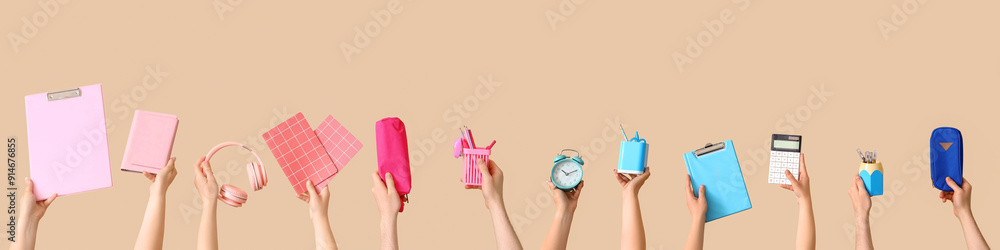 Many hands holding school supplies on beige background Many hands holding school supplies on beige background