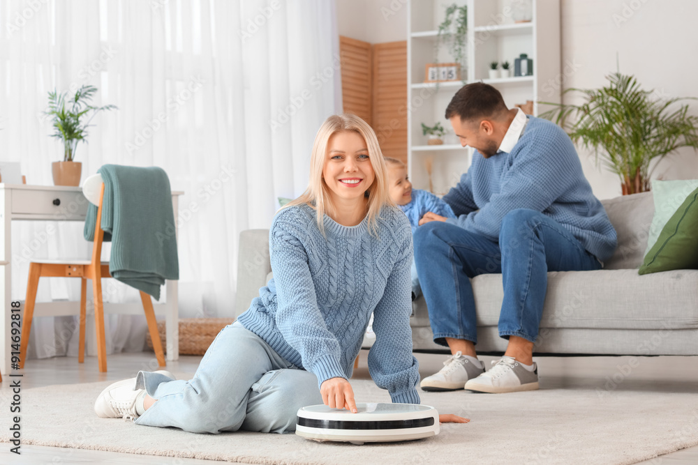 Happy mother with robot vacuum cleaner and her family at home Happy mother with robot vacuum cleaner and her family at home
