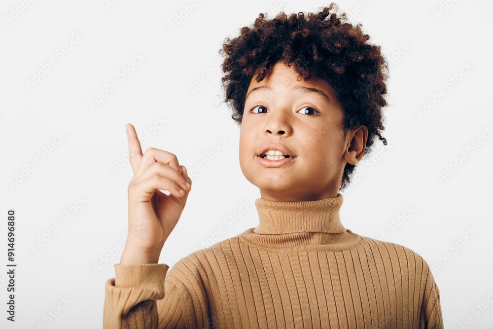 A curious young african american boy enthusiastically pointing at an imaginary object against a simple white background A curious young african american boy enthusiastically pointing at an imaginary object against a simple white background