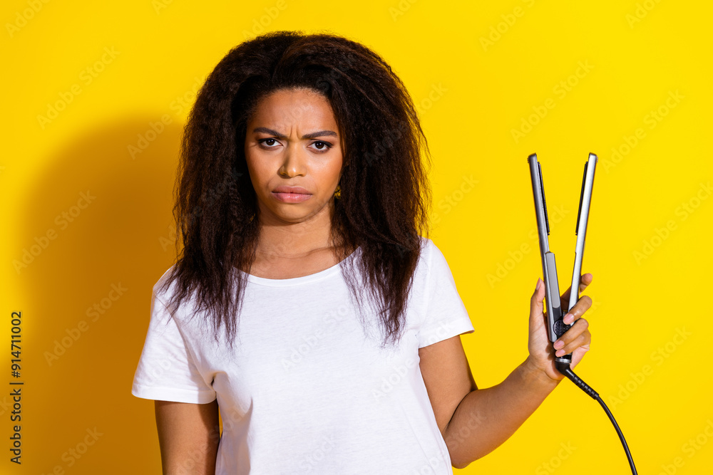 Photo of pretty young woman hair straightener wear t-shirt isolated on yellow color background Photo of pretty young woman hair straightener wear t-shirt isolated on yellow color background