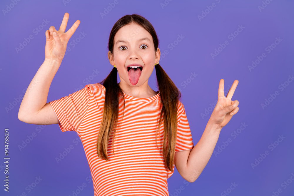 Photo portrait of lovely small girl stick tongue out v-sign dressed stylish red garment isolated on violet color background Photo portrait of lovely small girl stick tongue out v-sign dressed stylish red garment isolated on violet color background