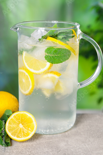 Freshly made lemonade with mint in jug on grey table outdoors