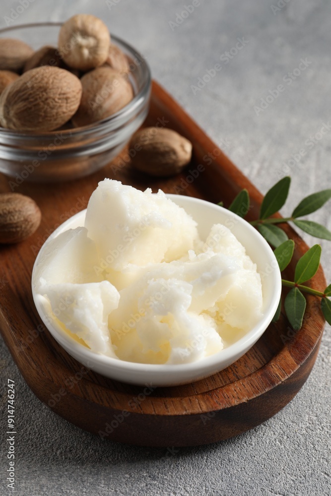 Natural shea butter in bowl, nuts, green leaves and plumeria flower on grey table Natural shea butter in bowl, nuts, green leaves and plumeria flower on grey table