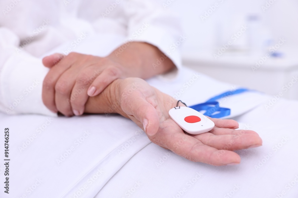 Senior woman with emergency call button on bed in hospital, closeup Senior woman with emergency call button on bed in hospital, closeup