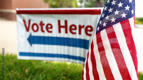 vote here sign blurred with American flag in focus at polling place precinct