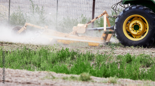 Large tractor mower attachment mowing a field of weeds