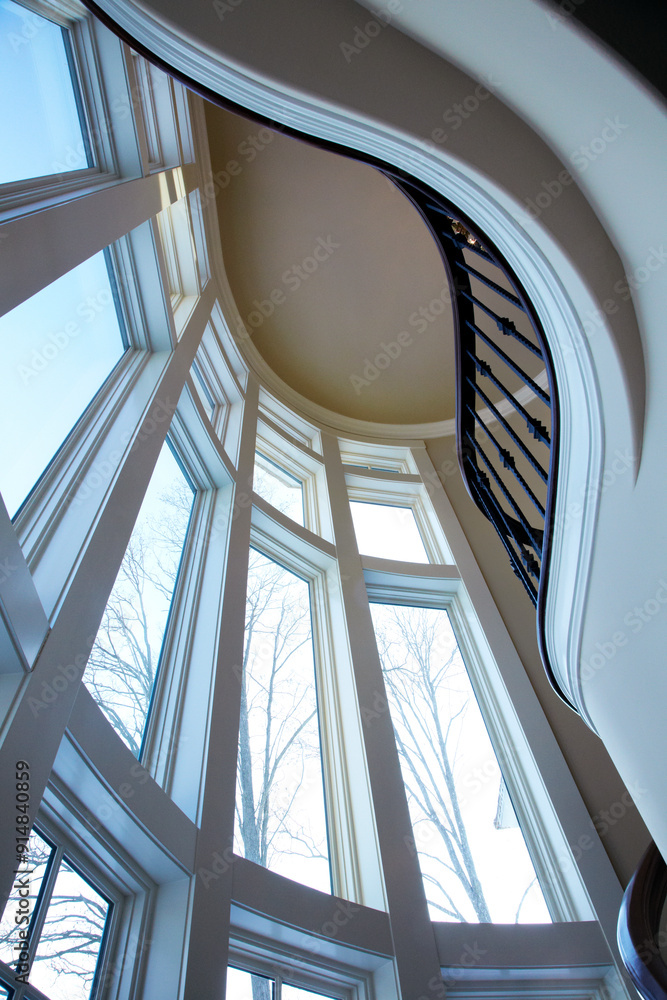 Obraz premium Looking up at a modern interior of large windows and spiral staircase as a beautiful vertical image