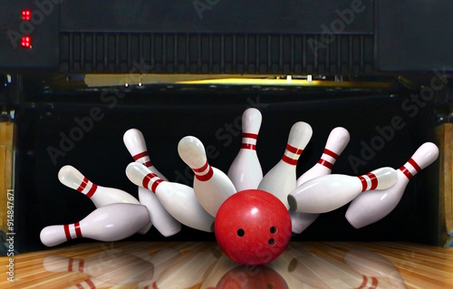 Foto Bowling strike hit with ball hitting ten pins in the alley