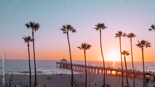 Palm trees and Pier on Manhattan Beach at sunset in California, Los Angeles, USA.
