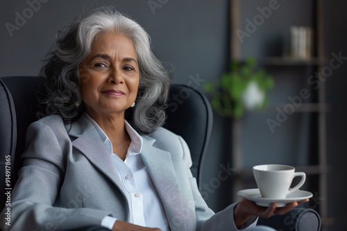 Confident Senior Woman in Business Attire Holding a Cup of Coffee in a Modern Office Setting