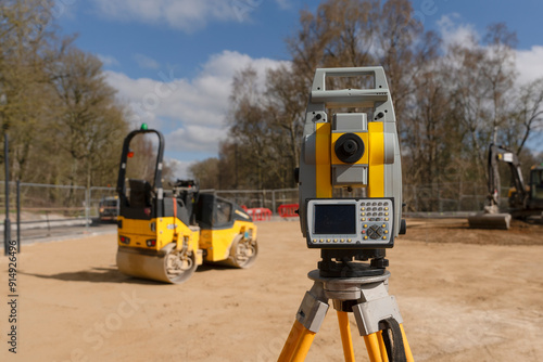 Принти на полотні Surveying Equipment in a Construction Site With Machinery and Trees Under  Blue