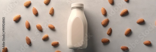 Almond Milk Simplicity: A Bottle of Plant-Based Milk with Scattered Almonds on a Minimalist Grey Background, Highlighting the Health Benefits of Vegan Nutrition. photo