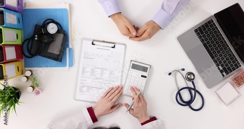 Doctor considers calculator for medical expenses for patient top view