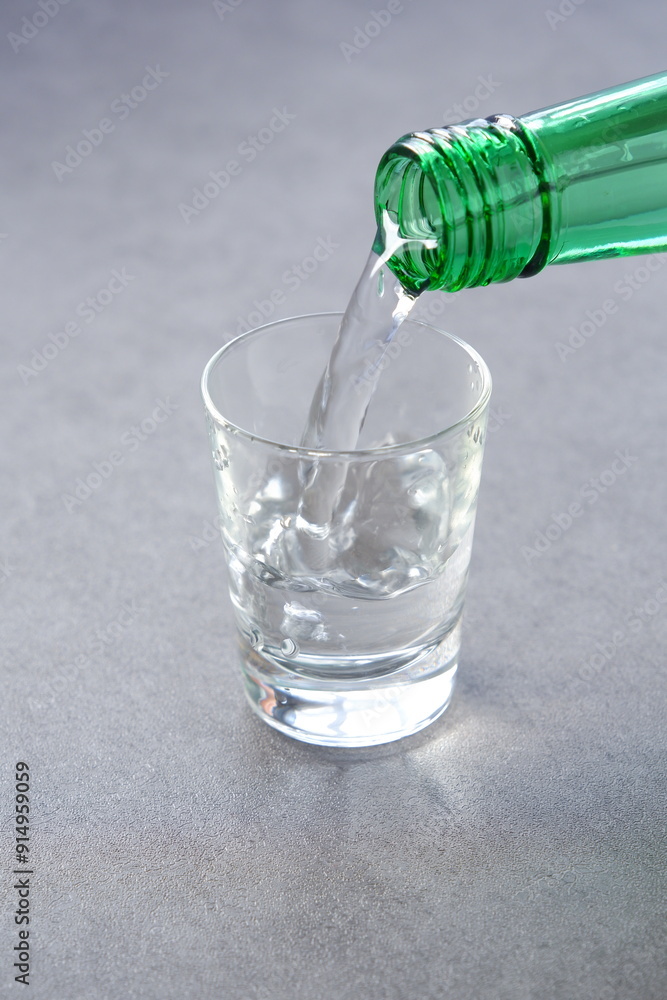 韓国の伝統的な蒸留酒、よく冷えた韓国焼酎(ソジュ)をグラスに注ぐ 韓国の伝統的な蒸留酒、よく冷えた韓国焼酎(ソジュ)をグラスに注ぐ