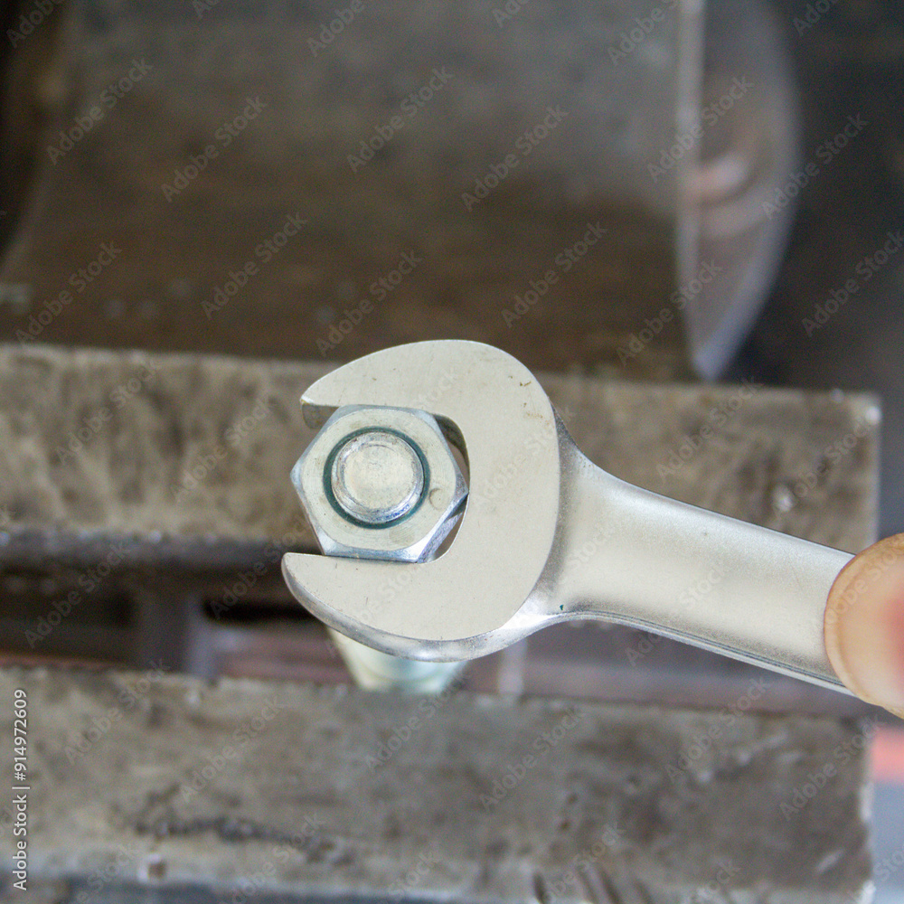Image of a mechanic's hand tightening a bolt with a wrench. DIY work in the workshop Image of a mechanic's hand tightening a bolt with a wrench. DIY work in the workshop