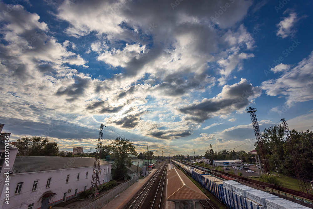 Trains line the platform beneath an expansive sky painted with dramatic clouds during the golden hour of late afternoon. Trains line the platform beneath an expansive sky painted with dramatic clouds during the golden hour of late afternoon.