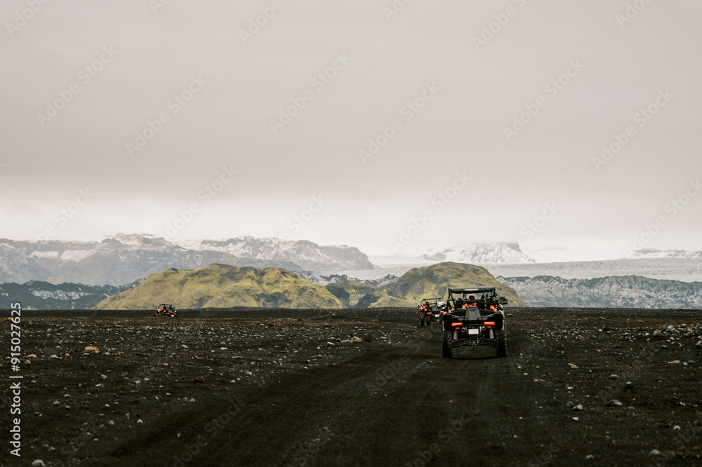 Buggy on black volcanic sand approaching mountains and glacial park Buggy on black volcanic sand approaching mountains and glacial park