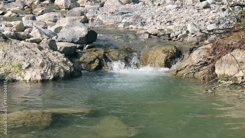 Static image of a river with clear, flowing water and stones. Static image of a river with clear, flowing water and stones.