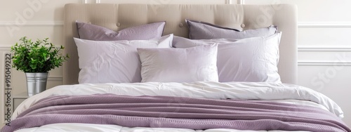  A bed adorned with multiple pillows and a plant in a vase by the headboard