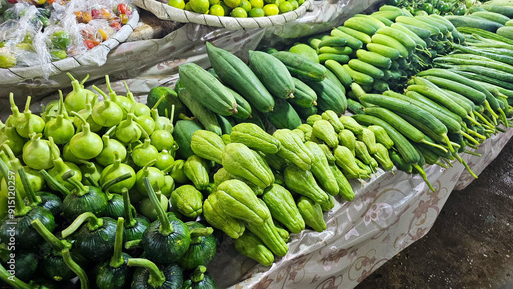 Fototapeta premium Fresh green vegetables, including gourds and cucumbers at a local market stall