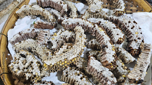 Dried honeycomb pieces containing bee larvae, displayed on a basket at a local market