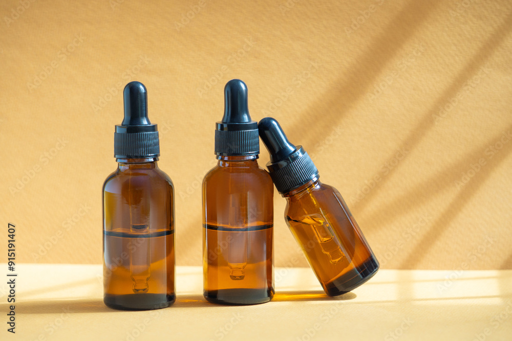 Set of serum vials in glass package with dropper lid. Essential oil for care of women's skin. Light brown background. Concept of body care, rejuvenation. Set of serum vials in glass package with dropper lid. Essential oil for care of women's skin. Light brown background. Concept of body care, rejuvenation.